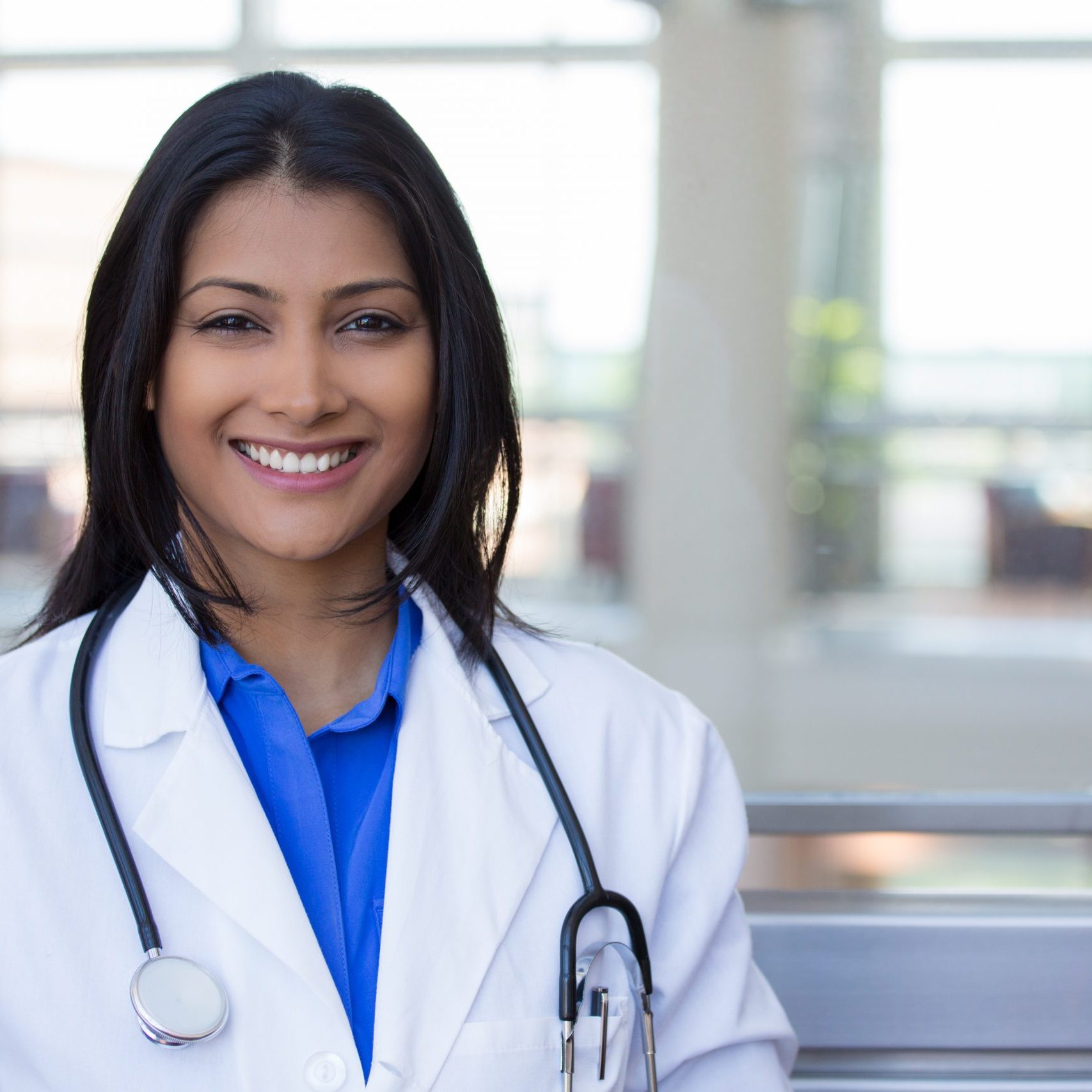 Closeup headshot portrait of friendly, cheerful, smiling confident female, healthcare professional with lab coat. isolated indoor clinic office background. Patient visit.